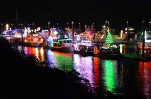 Boats on the river tied up at docks at night decorated with Christmas lights 
