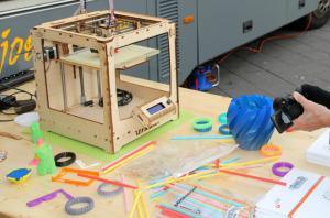 3D printer on table surrounded by printed objects 