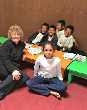 Rosemary Jeffrey sitting on floor with village children in new Himalayan classroom