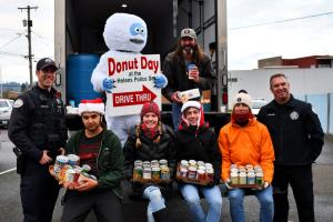 Volunteers, police officers, St. Helens mayor and person in Abominable Snowman suit pose in front of truck with canned food. 